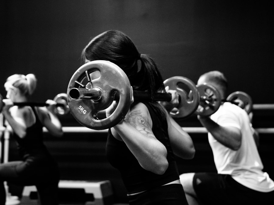 Group of members mid-rep with barbells in a darkened studio